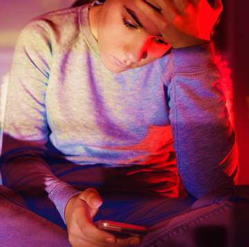 a young woman looking at her phone with her head in her hand